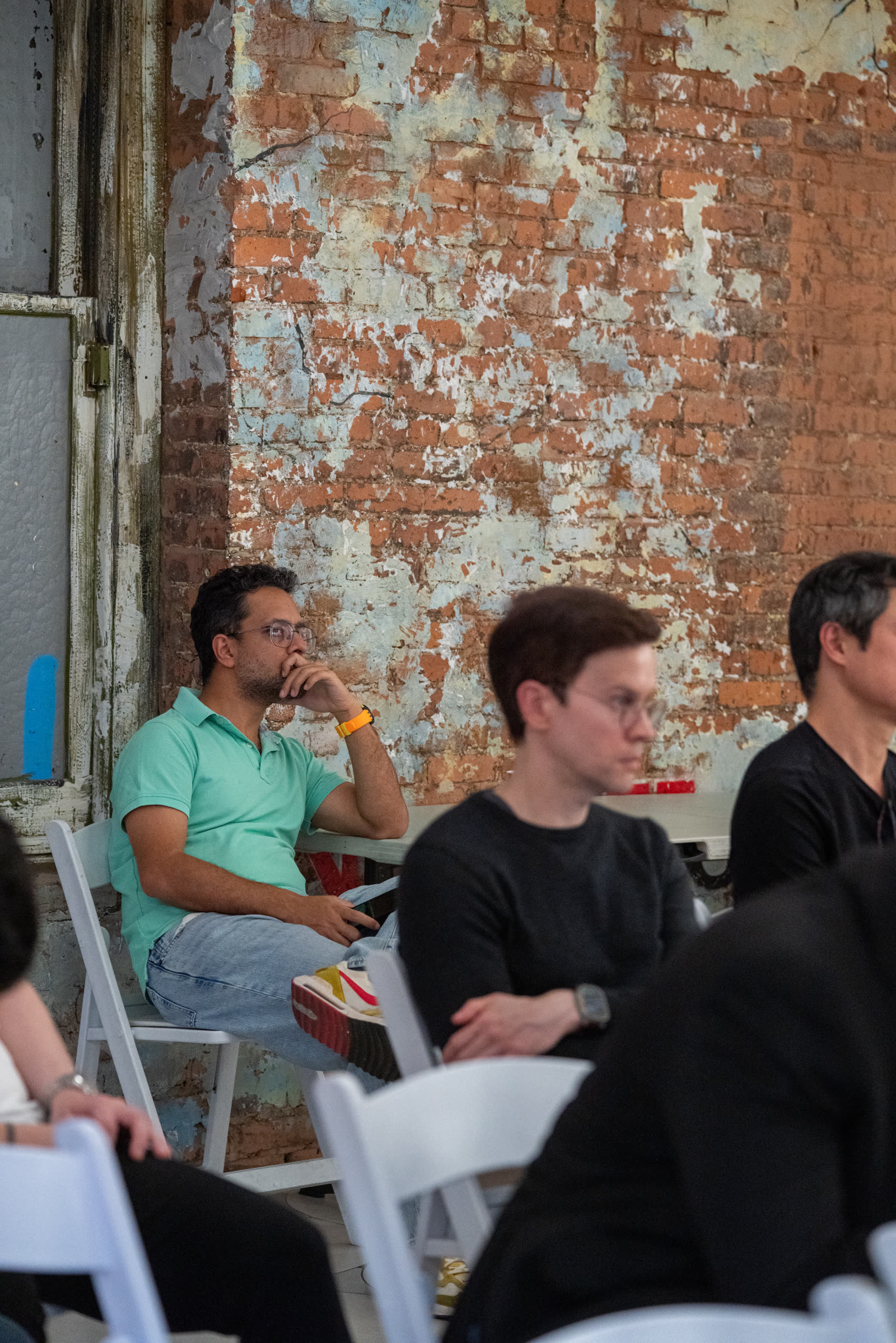 Attendees listening during the Impact Room panel against an exposed brick backdrop